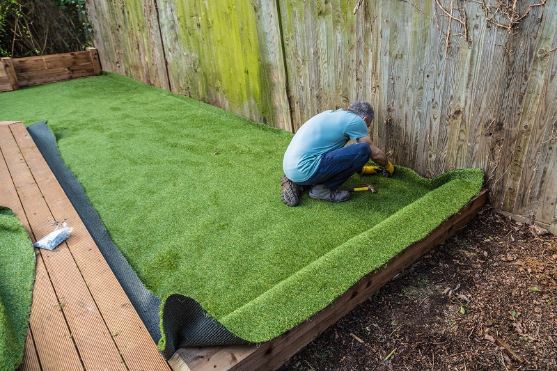 man hammering down artificial grass